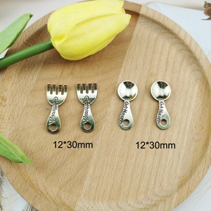 Antique silver DIY cutlery pendants with fork and spoon shapes on a wooden base