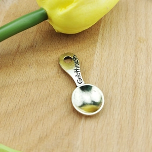 Macro view of spoon-shaped metal pendant with Get through engraving and hanging hole