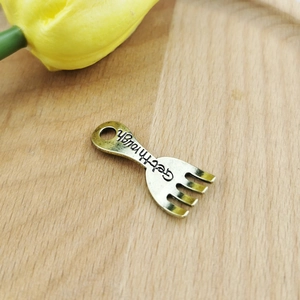 Detail view of antique gold cutlery fork pendant with Get through engraving for DIY jewelry