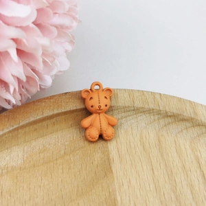 Detail shot of a matte orange bear pendant with stitching texture for DIY crafts