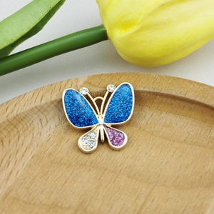 Detailopname van handgemaakte vlinderhanger met glinsterende blauwe en roze kristallen
