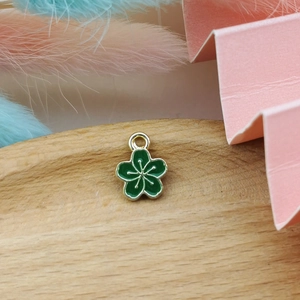 Macro view of dark green enamel flower charm with golden edges for jewelry making