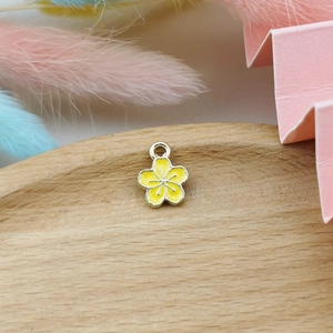 Macro detail of yellow five-petal flower alloy charm on a decorative wooden tray