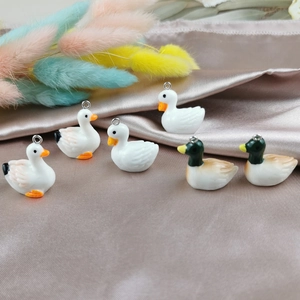 Pendentifs canard en résine avec boucles argentées sur fond de soie couleur champagne