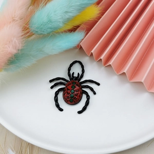 Dettaglio macro del ciondolo a ragno 3D con smalto rosso e verde su piatto bianco