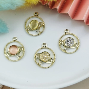 Set di 4 ciondoli Saturno in lega dorata con perle e strass su un vassoio bianco