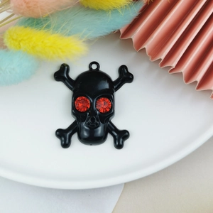 Detail eines schwarzen Emaille-Totenkopf-Anhängers mit roten Strassaugen und Ring