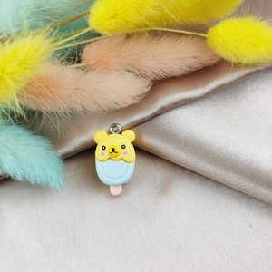 Detailed view of yellow bear ice cream resin pendant with metal ring on satin fabric