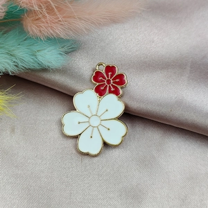 Détail d'un pendentif fleur de cerisier en émail bicolore rouge et blanc à bord doré