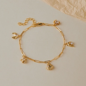 Détail d'une chaîne de cheville dorée avec pendentifs étoile de mer et coquillage