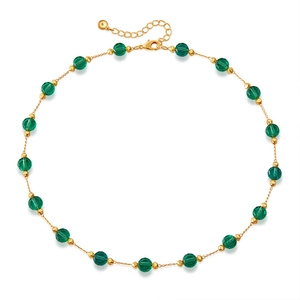 Flat lay of a gold necklace featuring dark green glass beads and adjustable lobster clasp