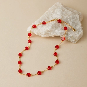 Detail of red faceted glass beads necklace with golden spacers and heart pendant