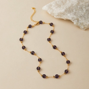 Detailed close-up of French vintage gold necklace with purple faceted beads and chain