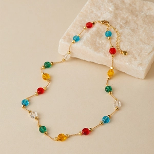 Detail of colorful faceted glass beads on a gold chain necklace with a lobster clasp