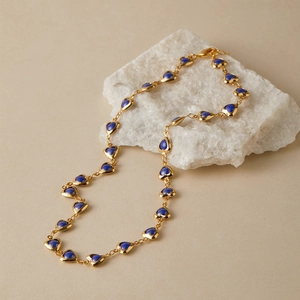 Detailed view of the 18K gold plated necklace with blue heart pendants on a white stone