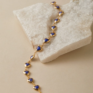 Detailed close-up of vintage gold heart-shaped link necklace with dark blue enamel inlay