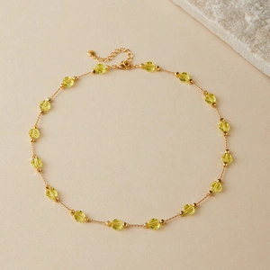 Close-up of beaded necklace with yellow faceted crystals and gold plated metal chain