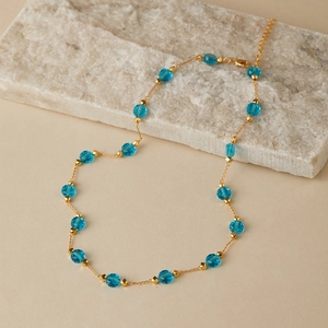 Close-up of a gold pearl necklace with blue faceted crystal beads and lobster clasp detail