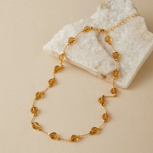 Close-up of amber faceted glass beads on a gold-plated necklace with adjustable chain