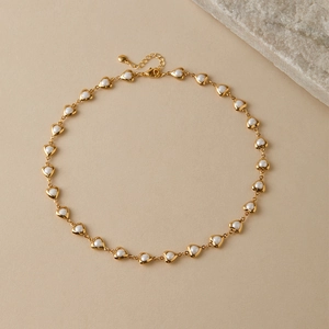 Detail of 18K gold plated heart frame necklace featuring elegant white pearl inlays