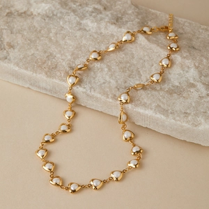 Close-up of gold chain necklace featuring multiple white heart-shaped pearl charms