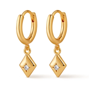 Macro shot of gold hoop earrings with rhombus pendant and white zircon inlay details