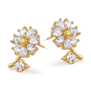 Detalle de pendientes de flor en oro de 18K con circonitas blancas y amarillas y hoja