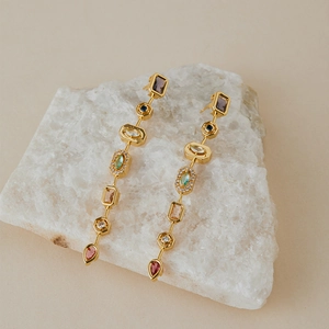 Orecchini pendenti in oro con pietre preziose geometriche su cristallo bianco