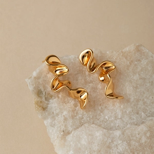 Vintage irregular twisted gold earrings displayed on a white textured mineral stone