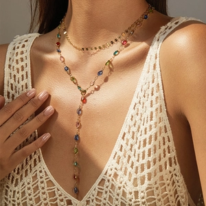 Détail d'un collier bohème doré multicouche avec cristaux colorés sur un mannequin