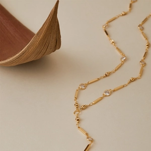 Elegant gold Y-shaped necklace with cubic zirconia and metal bars on a natural background