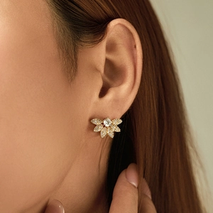 Elegant gold flower cluster earrings with sparkling zircon crystals worn by a model