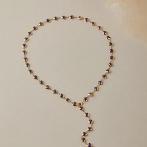 Détail d'un collier en Y doré avec petits pendentifs cœurs bleus et fermoir mousqueton