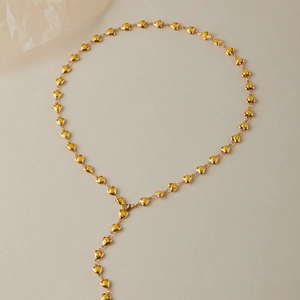 Détail des maillons dorés en forme de cœur sur une chaîne multicouche à texture raffinée
