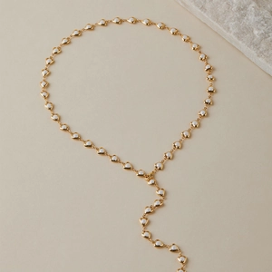 Détail du collier à maillons en forme de cœur doré avec incrustations en émail blanc