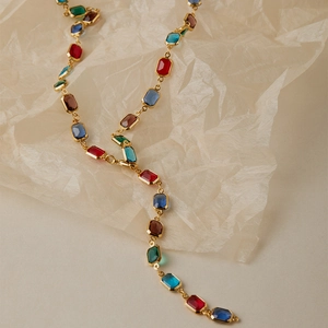 Vue macro d'un collier doré avec gemmes rectangulaires multicolores et design élégant en Y