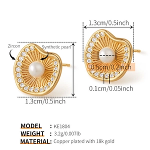 Détail macro de boucles d'oreilles dorées avec perle centrale et accents en zircon