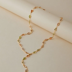 Détail d'un collier en Y doré avec pierres multicolores en forme de goutte et chaîne polie
