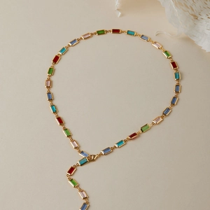 Détail de pierres rectangulaires multicolores sur un collier à chaîne dorée multicouche
