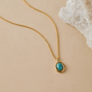 Close-up of a vintage 18K gold-plated necklace featuring a blue turquoise oval pendant