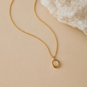 Detailed macro view of a gold-plated necklace featuring a polished rose quartz pendant
