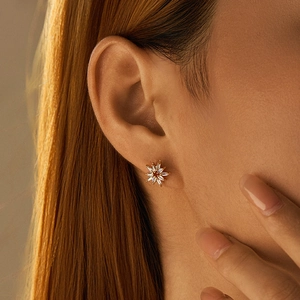 Macro side view of a starburst stud earring with sparkling zircons on a model
