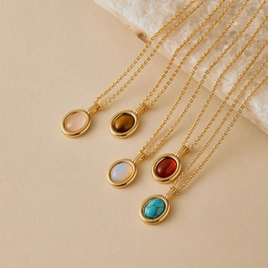 Close-up of five delicate gold chains with oval natural stone pendants in various colors