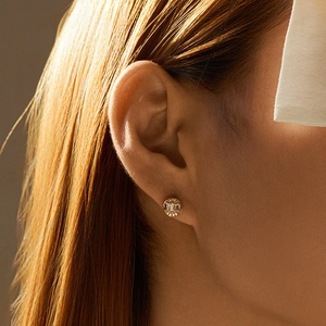 Elegant gold bow-shaped stud earrings with sparkling cubic zirconia on a female ear