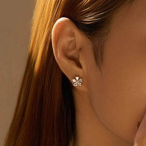 Close-up of elegant gold flower stud earrings with shimmering clear petal crystals on a model