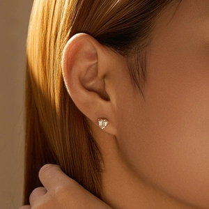 Macro shot of model wearing gold heart stud earrings set with sparkling zircon stones