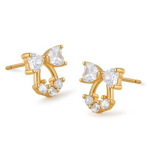 Close-up of golden bow earrings featuring heart-shaped crystals and small sparkling zircons