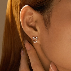 Macro shot of a tiny gold-plated bow stud earring featuring sparkling zircon stones