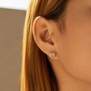 Elegant gold heart stud earrings with sparkling zircon stones worn by a model