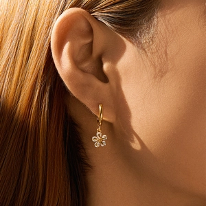 Detail einer goldene Blumen-Ohrring-Creole mit funkelnden Diamanten am Model